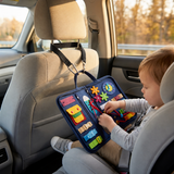 Le Cadeau Inoubliable — Le busy board attaché à l'appui-tête par sa sangle de trajet noire, en voiture