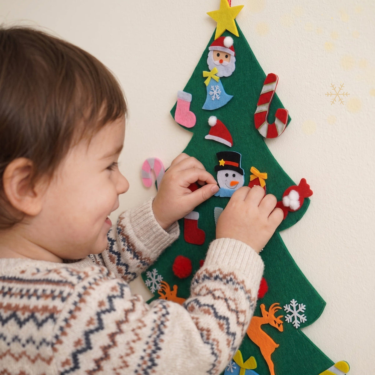 Gros plan d'un bébé qui accroche un ornement sur le sapin en feutrine