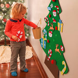Petit garçon décorant le sapin en feutrine Miloubo, vrai sapin en arrière-plan
